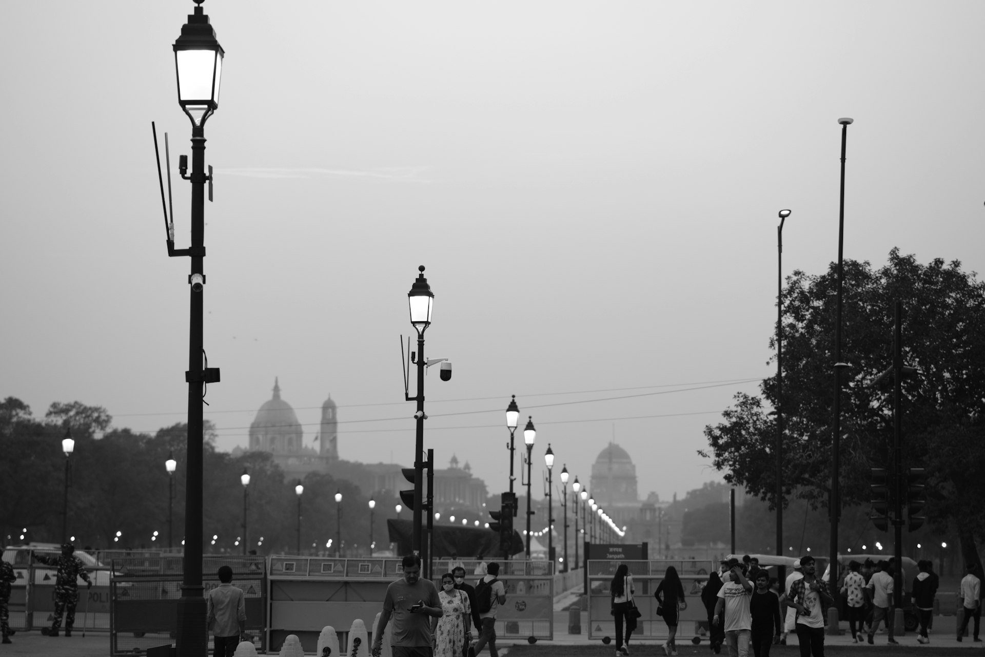 a group of people walking on a street with a domed building in the background